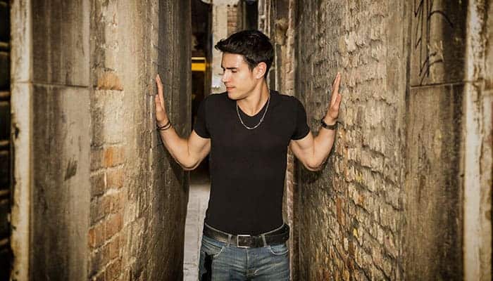 Man standing tensely in a narrow alley, showing feelings of anxiety.