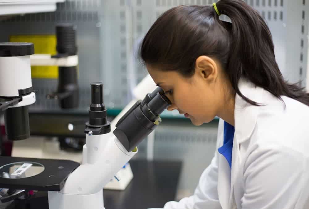 Researcher using a microscope in a laboratory study setting.