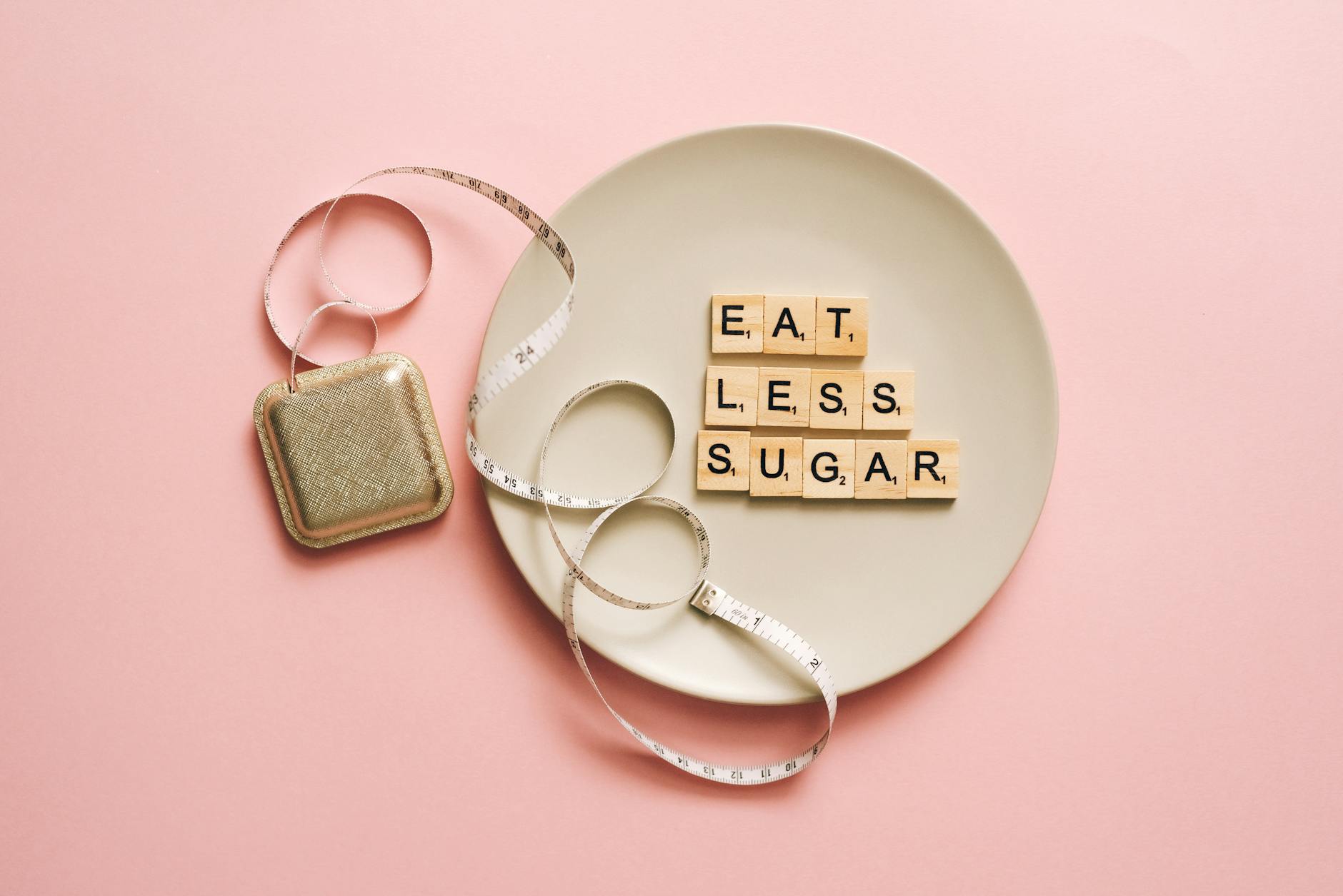 Plate with letter tiles reading eat less sugar beside a tape measure.