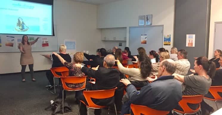 Speaker leading an NLP and hypnotherapy group session in a classroom.