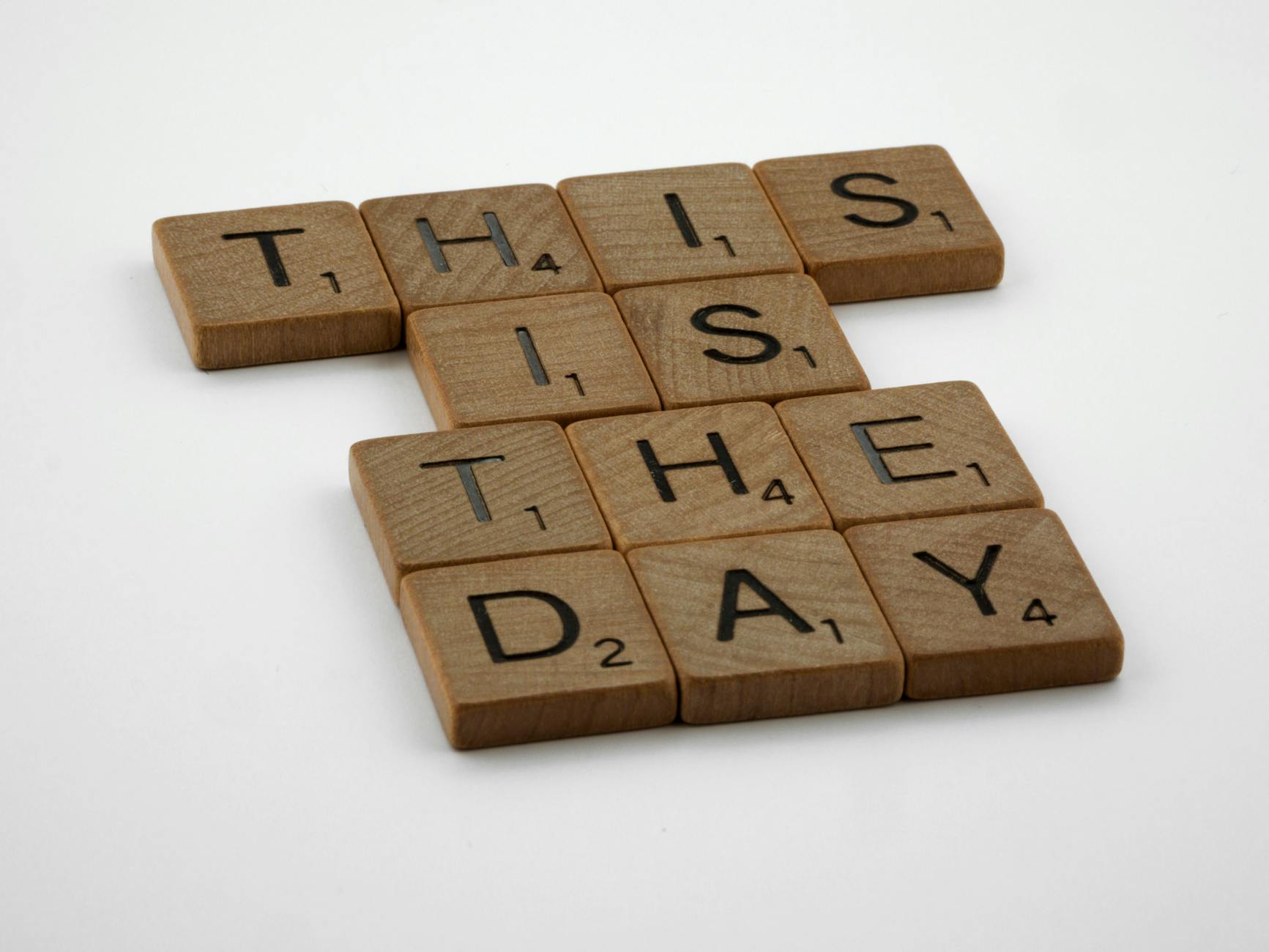 Wooden letter tiles spelling This Is The Day on a white background.